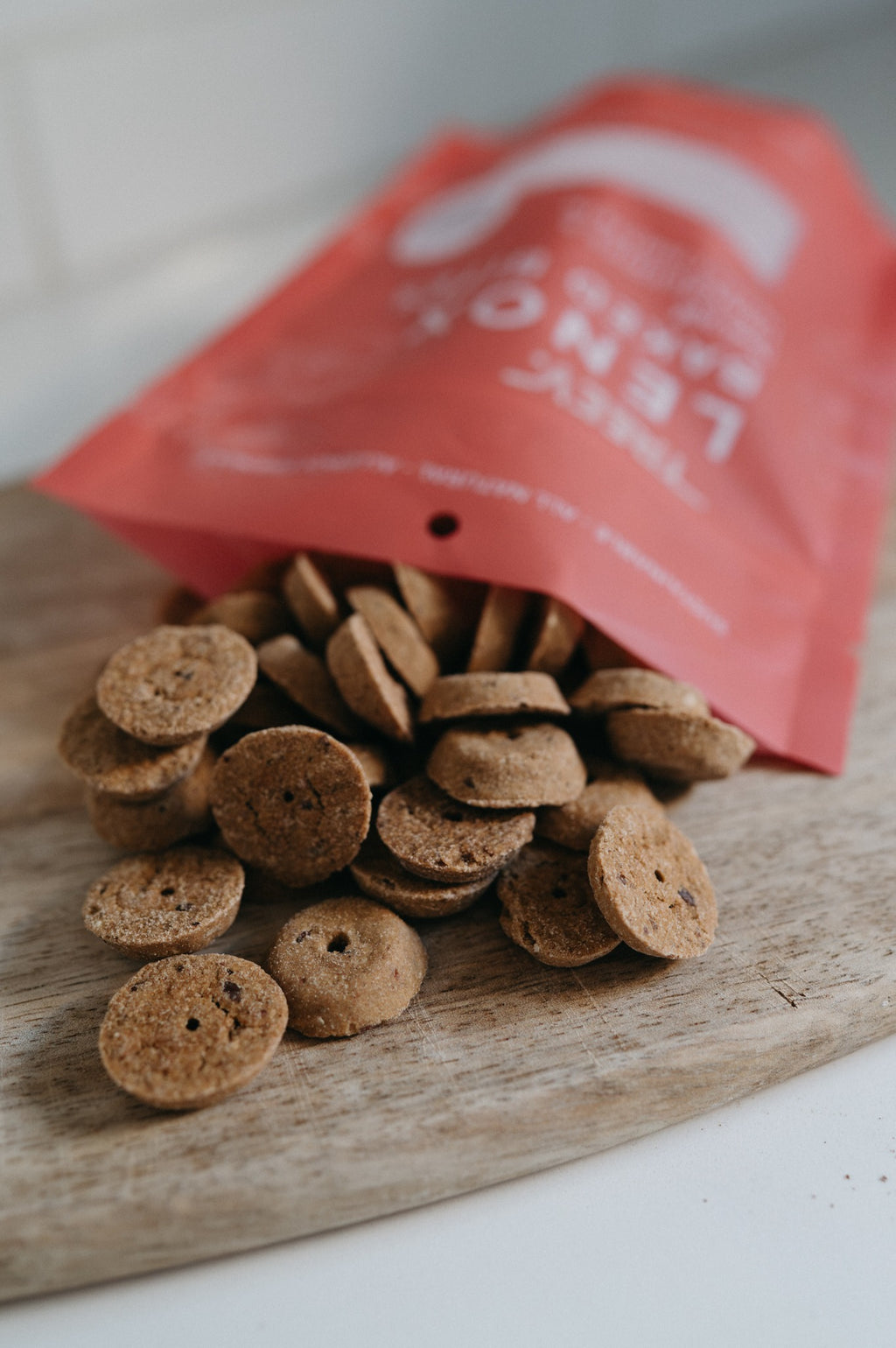 Round TREEV Lenox Baked Bites treats pouring out of the bag onto a wooden board