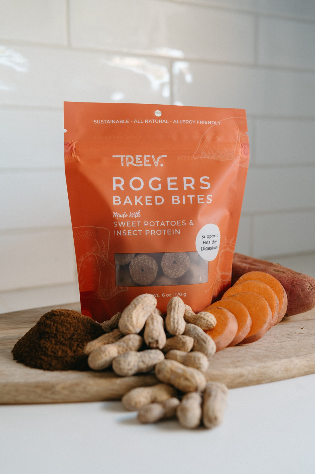 TREEV Rogers Baked Bites bag with sliced sweet potatoes, peanuts and powdered protein on a wooden board